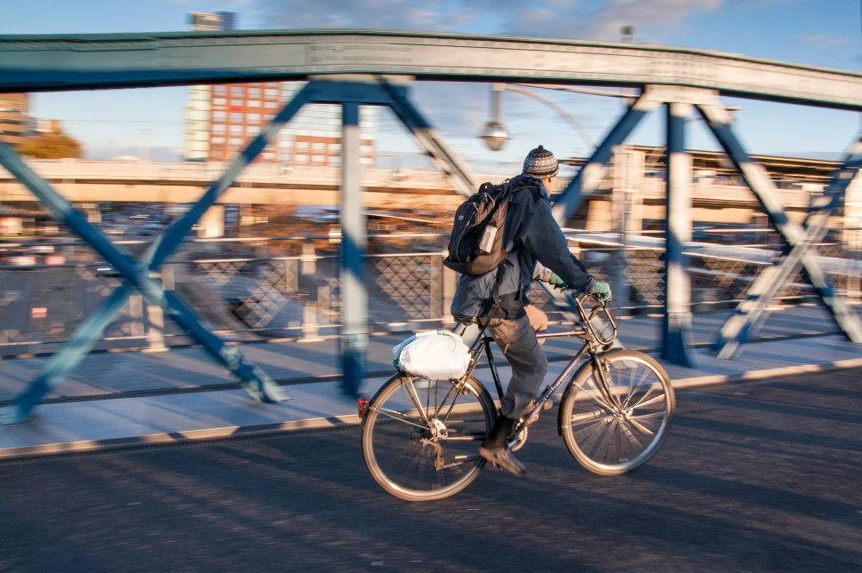 person riding bicycle beside gray metal railings of bridge preview